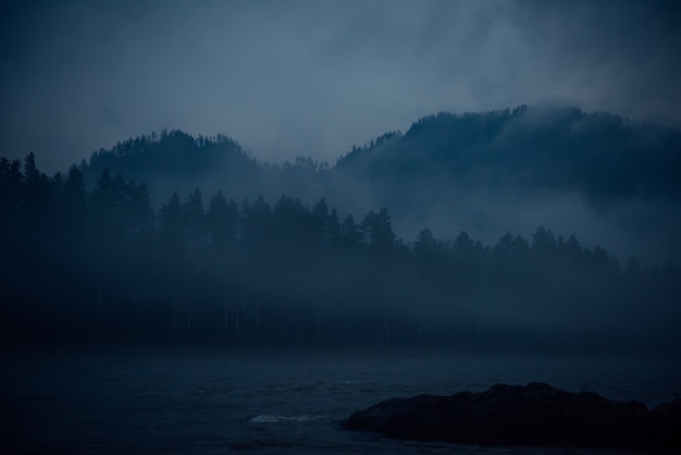 Blue haze, mystical misty morning. Fantastic landscape, thick fog over a mountain river at dusk.