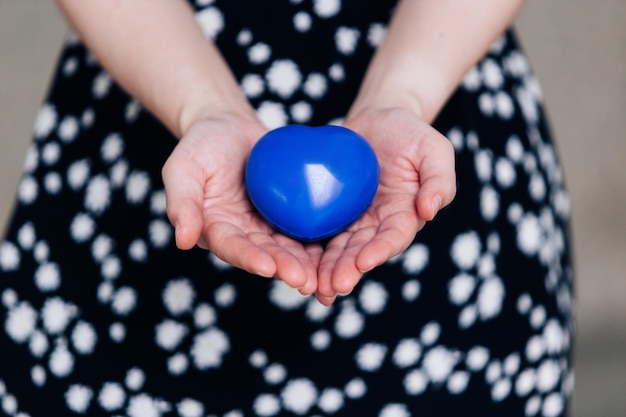 Blue heart in the hands of a woman in a polka dot dress