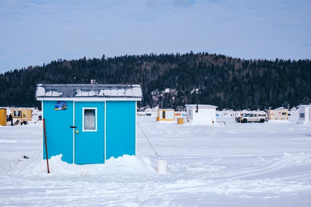 겨울날 퀘벡(캐나다) 라바이(La Baie)의 얼어붙은 사게네 피요르드(Saguenay Fjord)에 있는 푸른 얼음 낚시 오두막