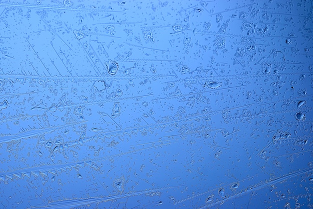 青い氷ガラスの背景、ガラス上の氷の表面の抽象的なテクスチャ、凍った季節の水