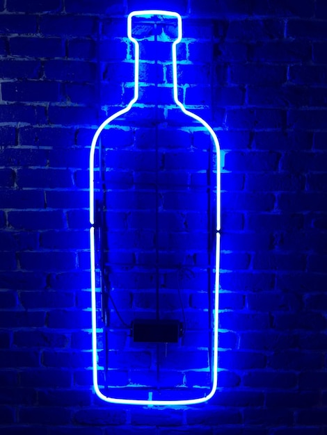 Photo blue illuminated bottle on brick wall