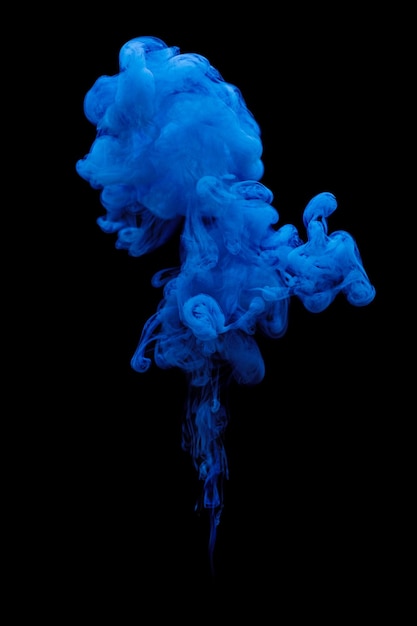 Photo blue ink swirling in water isolated on black background