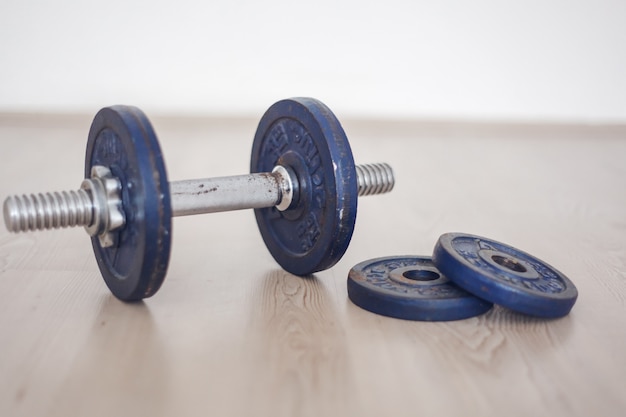 Blue iron dumbbell on the floor. Lifting weight. Workingout at home concept.