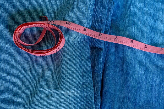 Blue jeans e un primo piano blu del nastro di misurazione misurazione delle dimensioni dieta e jeans sani con il rosso