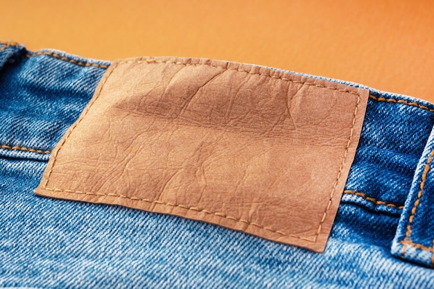 Blue jeans with a brown leather blank label closeup Jeans texture Fashion denim background for sewing copy space Label on clothing for indicate the size company