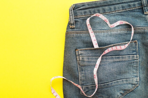 Blue jeans with measure tape in pocket in form of a heart concept of healthy lifestyle and diet