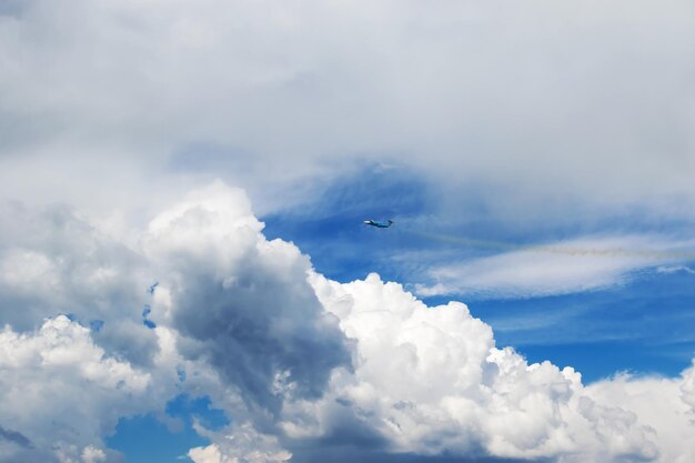 Blue jet fly producing a stream of smoke into the blue sky with clouds