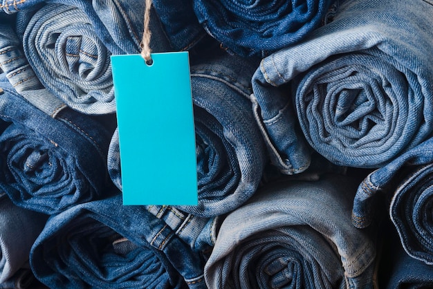 A blue label hanging from a pile of jeans