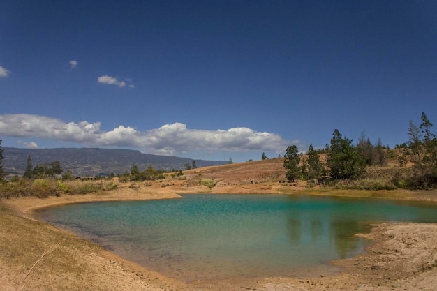 Голубое озеро в окружении деревьев и голубого неба