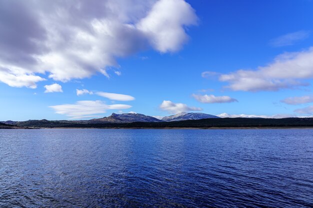 Blue lake with cloudy sky and mountains on the horizon