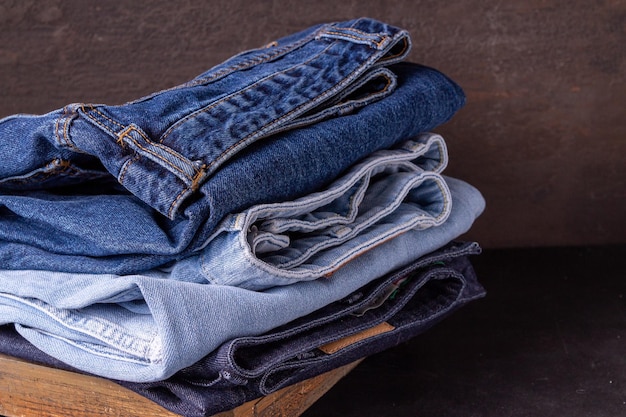 Blue and light blue jeans lie in a stack on a brown background