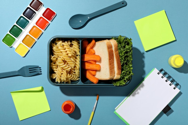 음식 과 그림 을 그리는 물품 이 있는 파란색 점심 상자