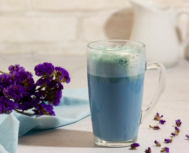 Tè matcha blu in un bicchiere di latte sul tavolo.