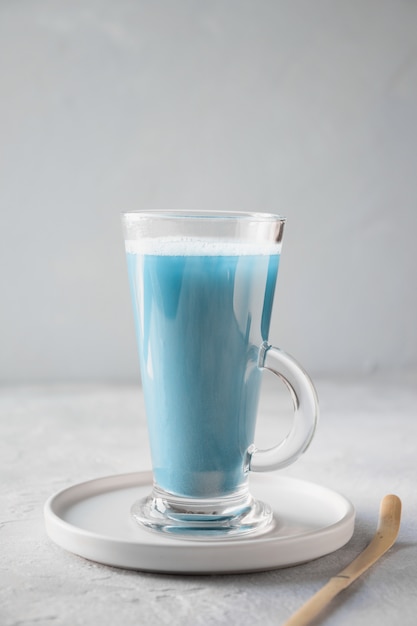 Blue matcha tea in latte glass on grey table 