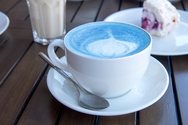 Синий чай маття в белой чашке на столе с десертом