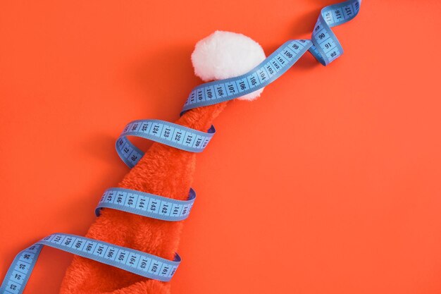 Blue measuring tape and red santa claus hat on red background\
weight loss concept size measurement