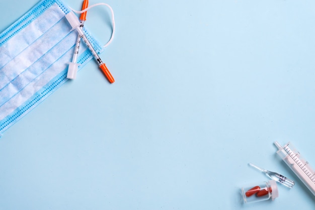 Blue medical mask and disposable syringe. Medical supplies. Copy space