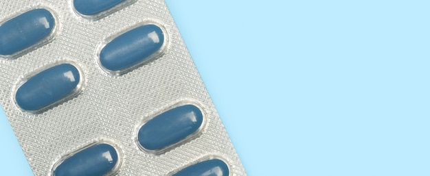 Blue medical pills in a blister on a light blue background with copy space