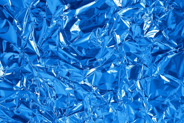 Blue metallic foil leaf shiny texture background, crumpled wrapping paper.