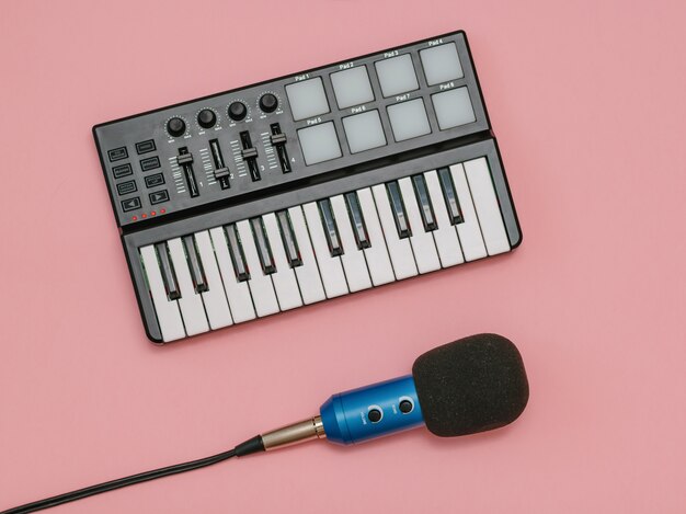 Blue microphone with wires and music mixer on pink surface. The view from the top.