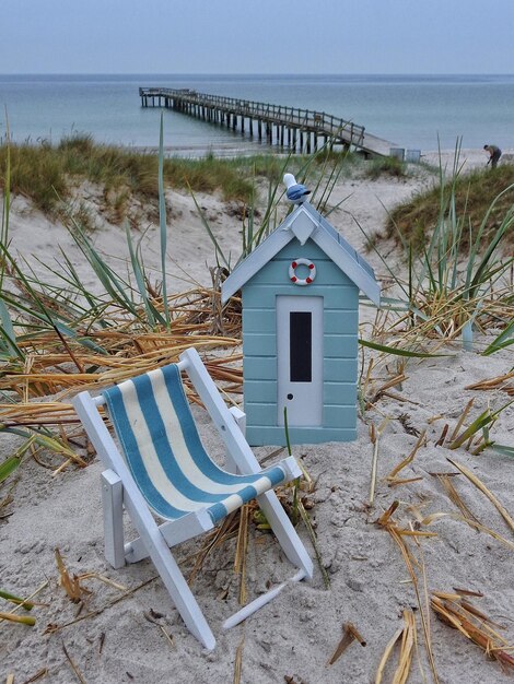 Foto cabina in miniatura blu e sedia a sdraio sulla spiaggia sabbiosa