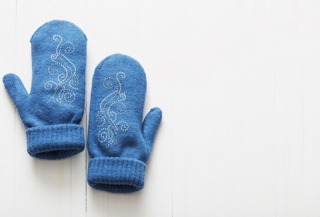 Blue mittens on white wooden background