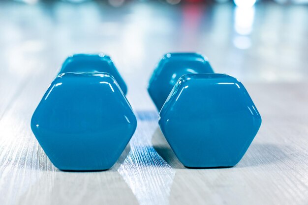 Blue modern dumbbells in the foreground on a wooden white floor