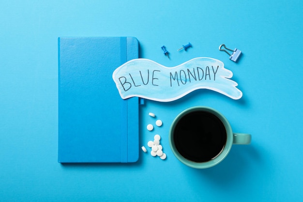 blue monday text stationery and cup on blue background top view