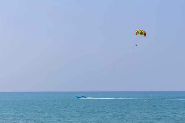 Фото Синяя моторная лодка на горизонте в андаманском море катит человека под парашютом на мелководье dofcopy space