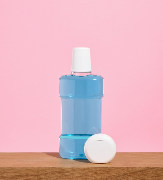 Blue mouthwash and dental floss on a wooden table Oral care accessories