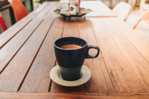 カフェの木製テーブルにホットチョコレートの青いマグカップ