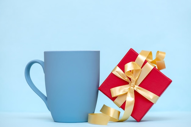 Blue mug with a gift box on a blue background. Universal background