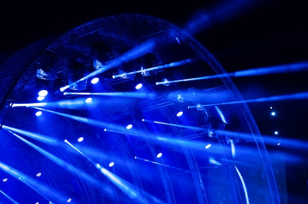 Luce al neon blu raggi di luce provenienti dall'illuminazione di un concerto su uno sfondo scuro sopra lo schermo del proiettore.