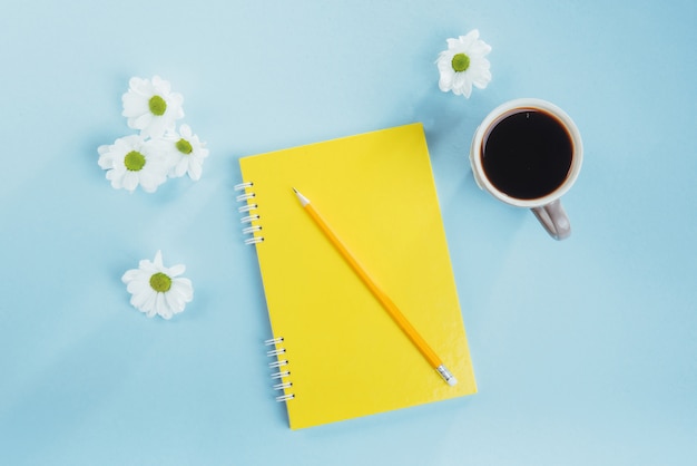 On the blue  notebook pencil, ruler and white flowers