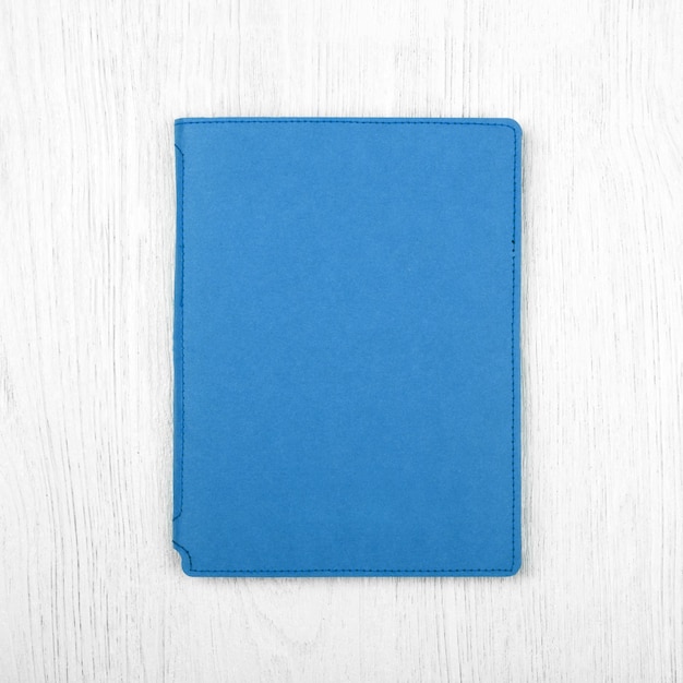 Blue notebook on white wooden table top view