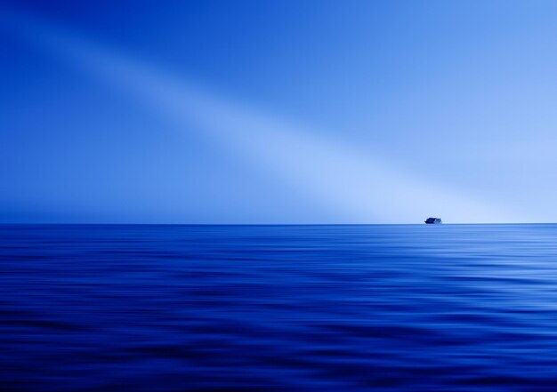 Blue ocean horizon ray of light abstraction with ship