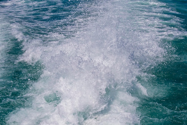 Blue ocean sea water wave with fast yacht boat wake foam of prop wash Thailand