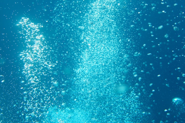 泡で水中から青い海の波。光線が透けて見えます。背景のための素晴らしい青い水の泡。