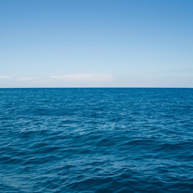 A blue ocean with a sky that has a few clouds