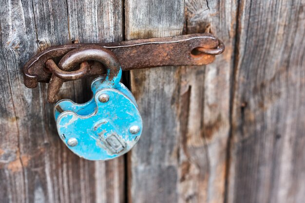 Lucchetto sbloccato arrugginito vecchio blu sulla porta di legno