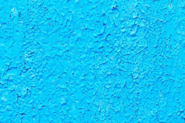 Blue paint is peeling off on old metal surface