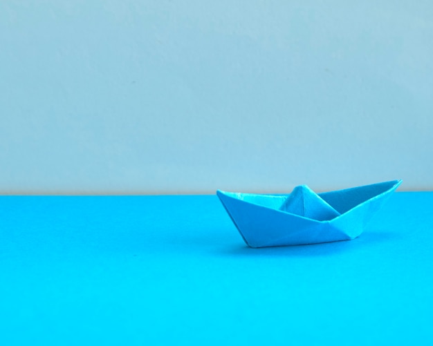 Blue Paper boat on cyan background.  