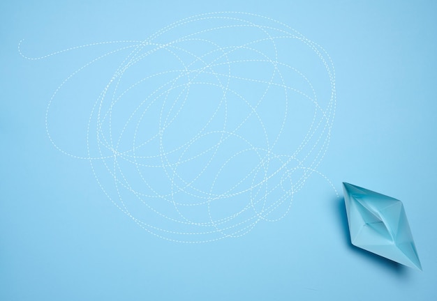 A blue paper boat and a long tangled path symbolizing the concept of a challenging journey