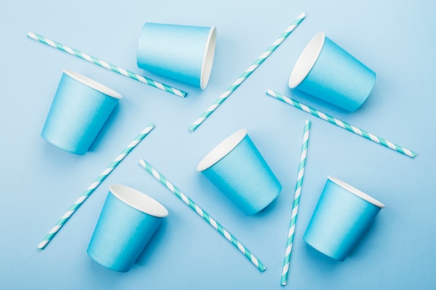 Blue paper cups and blue-white straw on blue