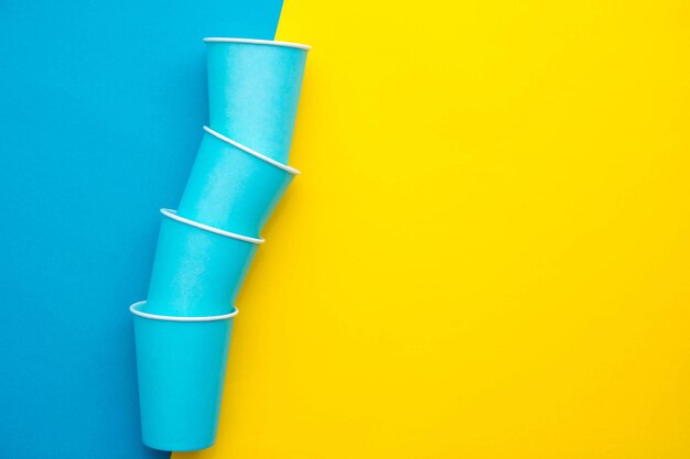 Blue paper disposable cups yellow and blue background