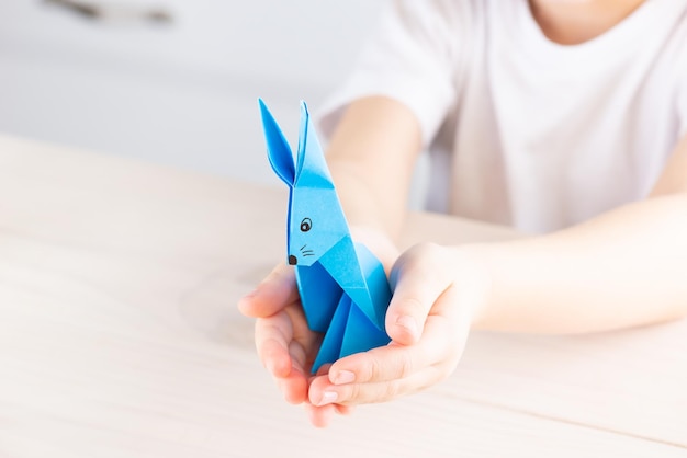 Blue paper rabbit in the hands of a child