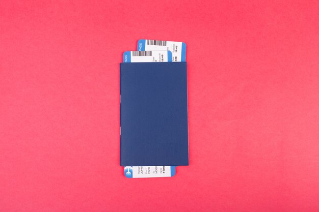 Blue passport with two flight tickets in it on pink  top view