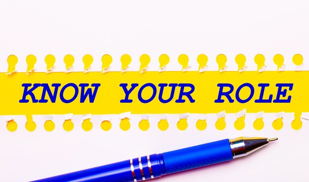 Blue pen and white torn paper stripes on a bright yellow background with the text KNOW YOUR ROLE