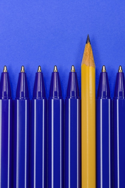 Penne blu e una matita gialla su sfondo blu