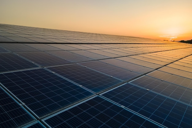 Blue photovoltaic solar panels mounted on building roof for producing clean ecological electricity at sunset Production of renewable energy concept